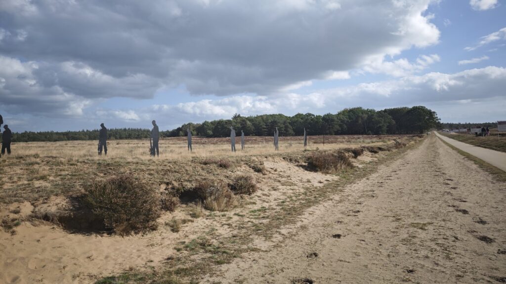 Wandelen op de Ginkelse Heide: silhouetten van Airborne-soldaten langs een zandpad onder wolkenlucht